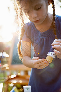 手绘连衣裙女孩女孩在花园里把涂料挤到手指上背景