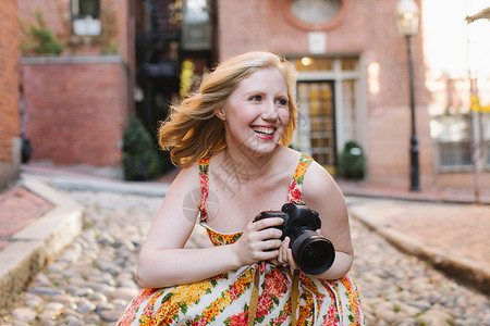 年轻女摄影师蹲在落满树叶的街道上中等长度的头发高清图片素材