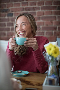 女人坐在咖啡厅里端着咖啡微笑图片