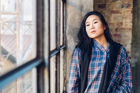 窗边靠着砖墙沉思的女人图片