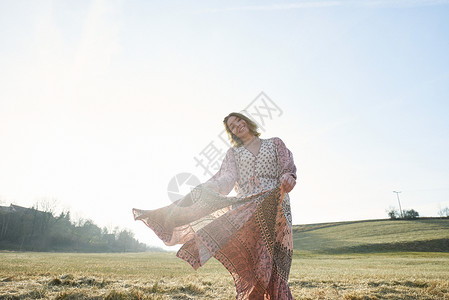 嬉皮风格的女人在阳光下田里跳舞的肖像背景图片