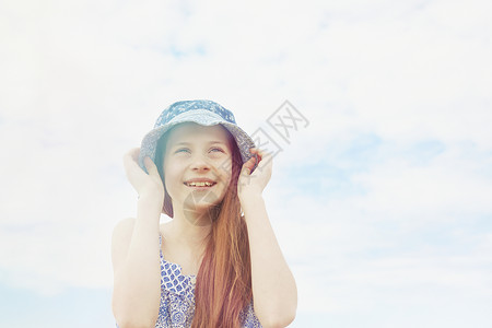 女孩用手摸着她头上的太阳帽子图片