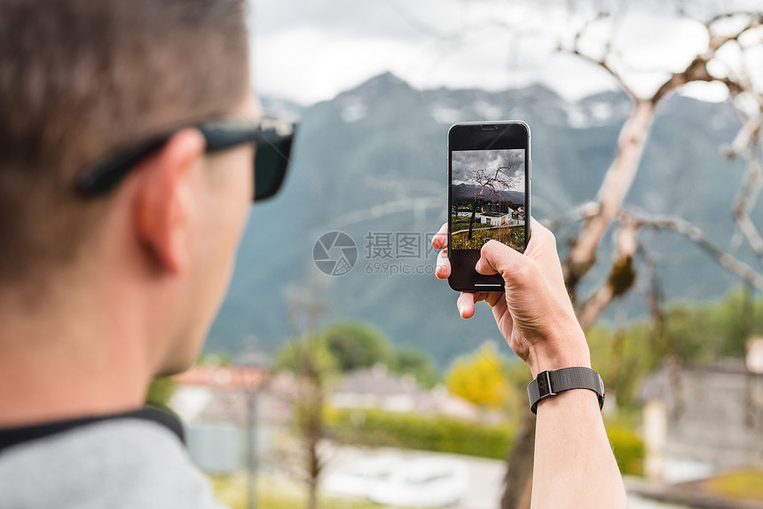 在意大利维内托山村用手机拍照片的男旅游者图片