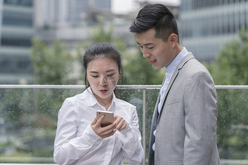 在上海市年轻男女商人在看手机图片