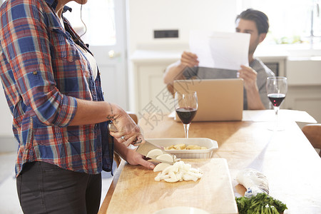 妇女在厨房餐桌上切菜男朋友看书图片