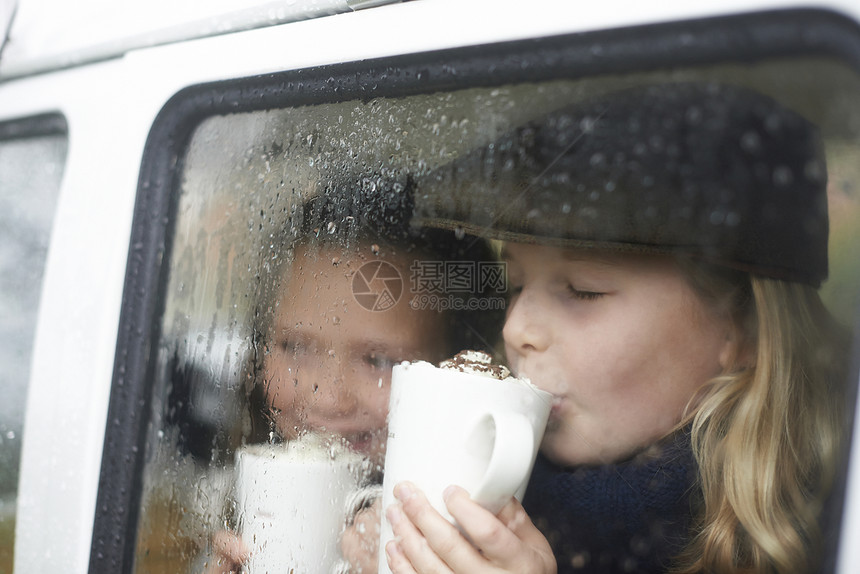 女孩在野营车内喝着热巧克力向外看图片