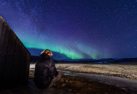坐在冰岛斯科加北光前的人背景图片