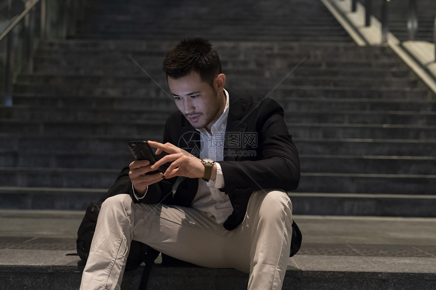 年轻商人坐在城市的楼梯上看手机意大利米兰图片