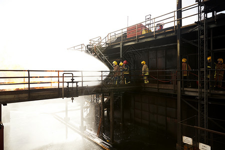 消防员培训在培训设施的高架走道上向火灾喷水高清图片
