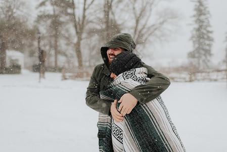 在雪地上用毯子包着妻子的男人加拿大高清图片素材