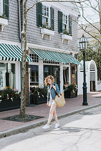 一名年轻女子提着包袋在街上漫步图片