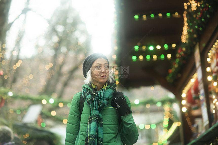 圣诞节走在街上看着商店橱窗的女人图片