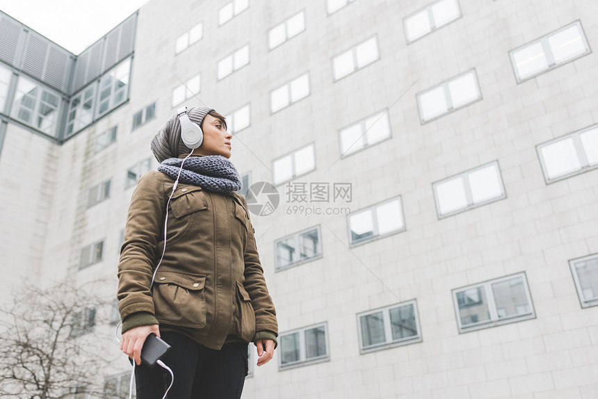中成年妇女低角度收听耳机观看城市办公室街区图片