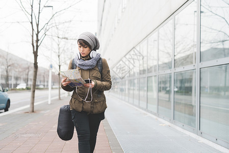 拿着手机走在城市人行道的女人图片
