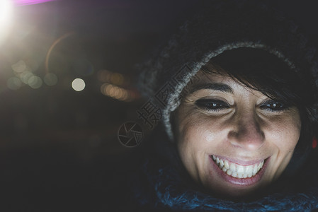 夜里戴着毛衣帽的女人在微笑背景图片