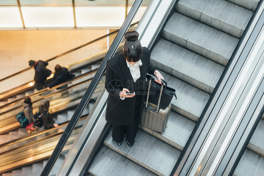 在扶梯上使用移动电话的意大利米兰女商人图片