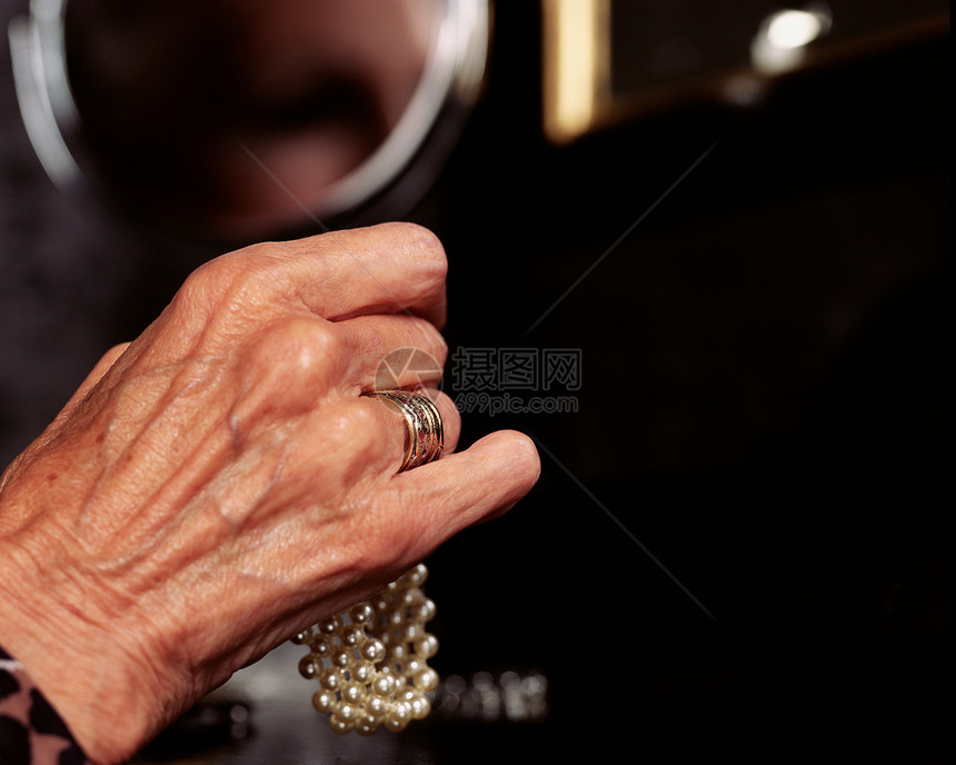 一个拿着珍珠手镯的老妇人的手图片