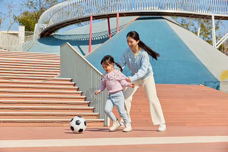 踢足球小女孩妈妈陪女儿户外玩耍踢足球背景
