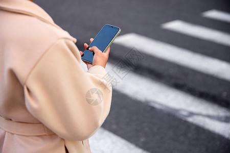 提高安全意识青年女性过马路看手机特写背景