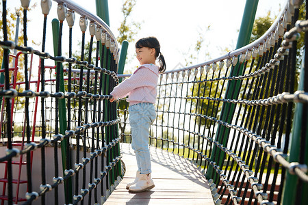 站在桥上玩耍的孩子小女孩在公园娱乐设施玩耍背景