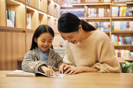 母亲陪孩子坐在书店里阅读图片