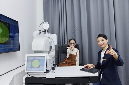 验光师在验光机器边指导小女孩检查视力图片