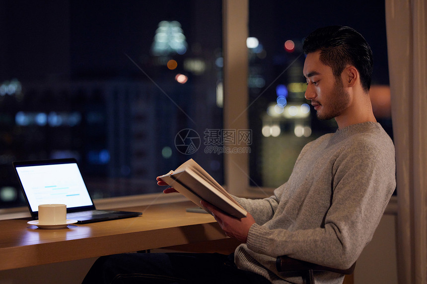 夜晚坐在书桌前看书的居家男性图片