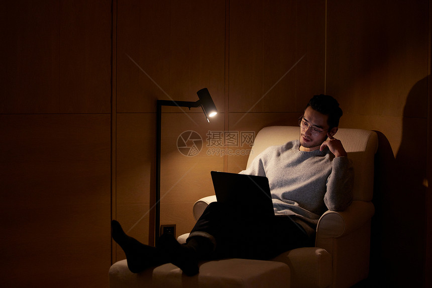 夜晚躺在沙发上使用电脑的成熟男性图片