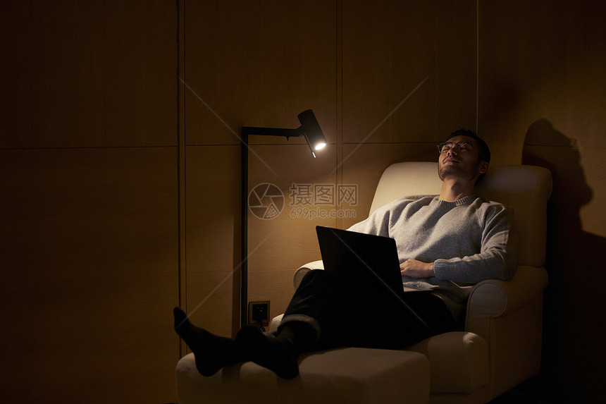 躺在沙发上拿着电脑休息的男性图片