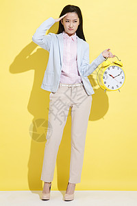 一个黄色的闹钟青年商务女士拿着钟表背景