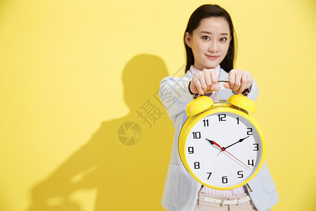一个黄色的闹钟青年商务女士拿着钟表背景