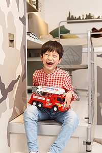 小男孩在卧室里拿着玩具车高清图片