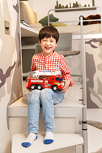 快乐小男孩在卧室里拿着玩具车高清图片