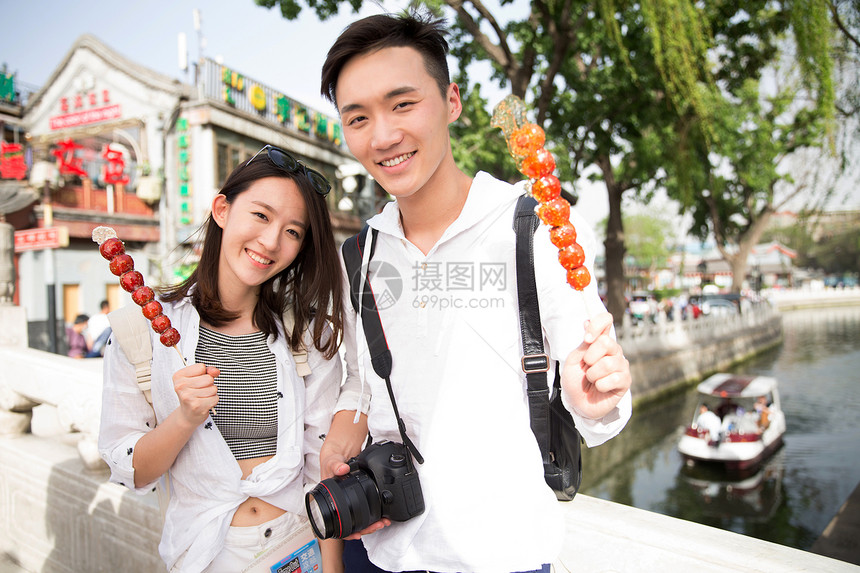 旅途青年情侣旅游拿着糖葫芦图片