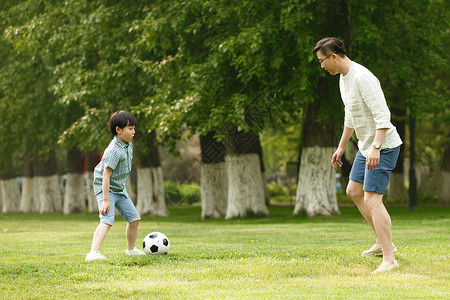 快乐童年踢球快乐父子在草地上踢足球背景