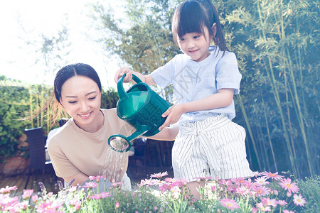 年轻的母亲和女儿在浇花植物高清图片素材