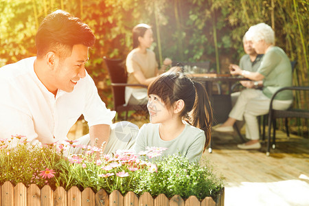 父亲和女儿幸福家庭在庭院里植物高清图片素材