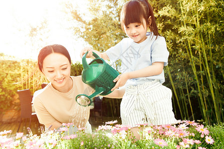 年轻的母亲和女儿在浇花夏天高清图片素材