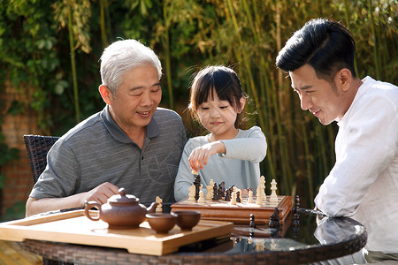 休闲追求中式庭院欢乐祖孙三代在庭院里下棋图片