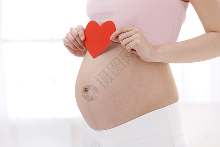 保护皮肤孕妇拿着心形剪纸放在肚子上背景