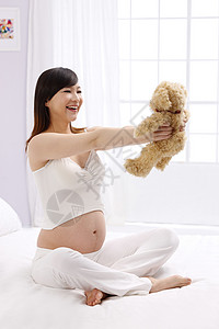腹部垂直构图母亲孕妇拿着玩具熊图片素材