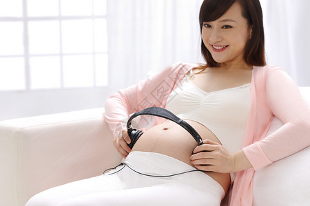 仅女人爱健康生活方式孕妇把耳机放在肚子上高清图片