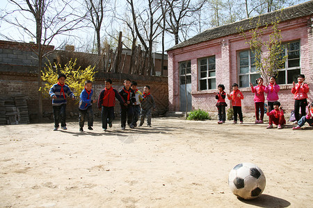 乡村小学生在学校里踢足球高清图片