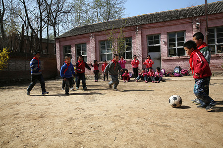在运动的球乡村小学生在学校里踢足球背景