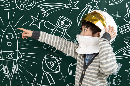 空间感知戴着航天员头盔的小男孩站在黑板前背景