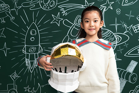 抱着航天员头盔的小女孩站在黑板前高清图片