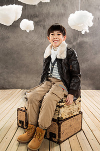 小男孩坐在复古行李箱上图片