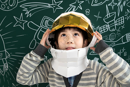 空间感知东方人天文学站着戴着航天员头盔的小男孩站在黑板前背景