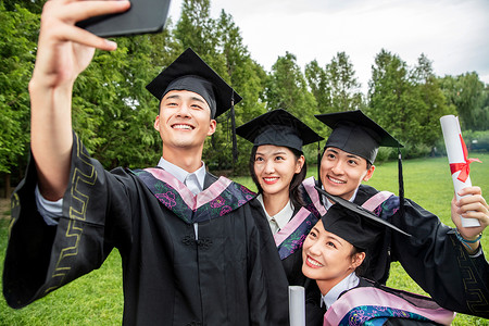 四个身穿学士服的大学生用手机自拍幸福高清图片素材