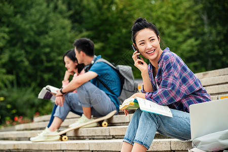 滑板运动学生快乐的大学生坐在台阶上打电话背景